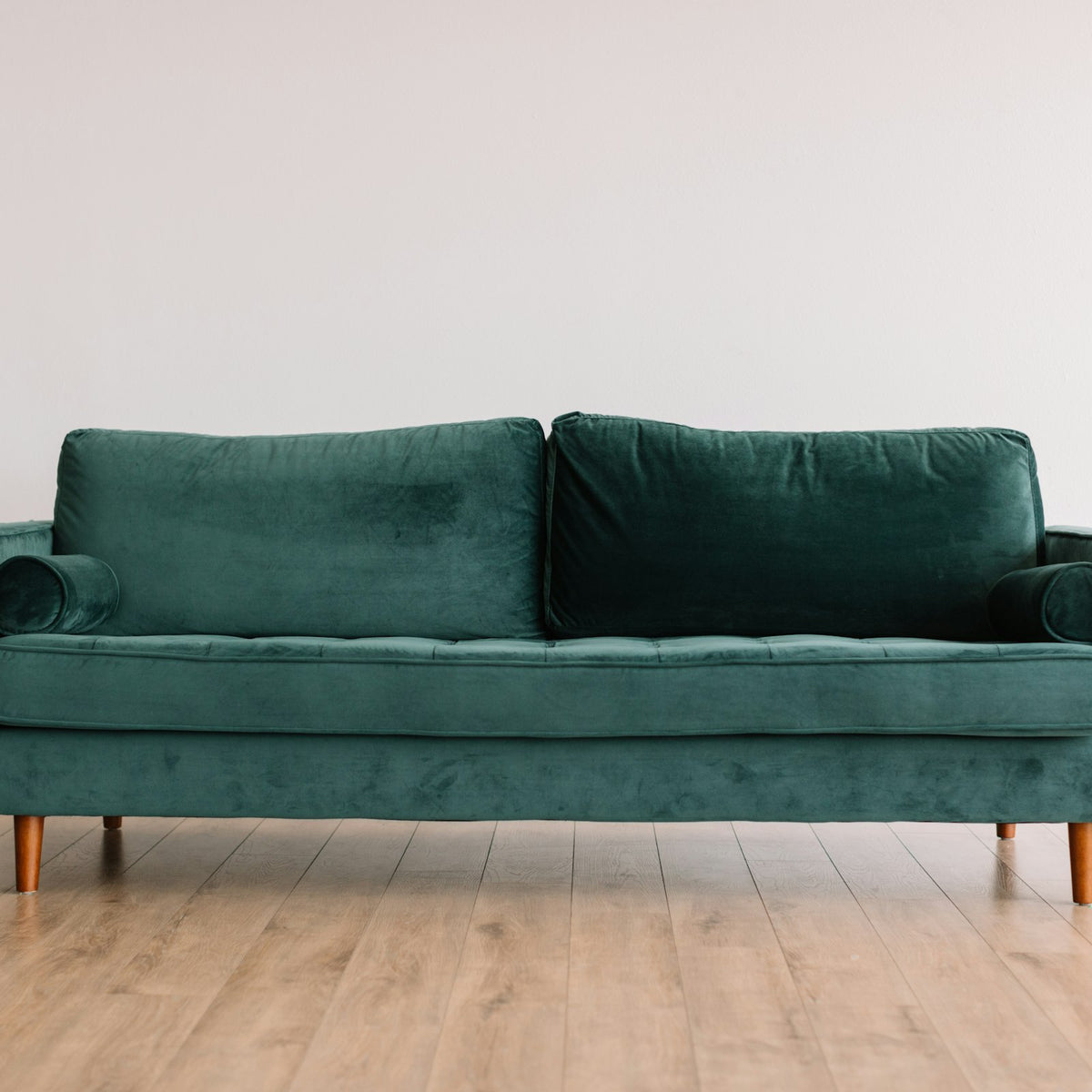 Emerald green velvet sofa on slim wooden legs