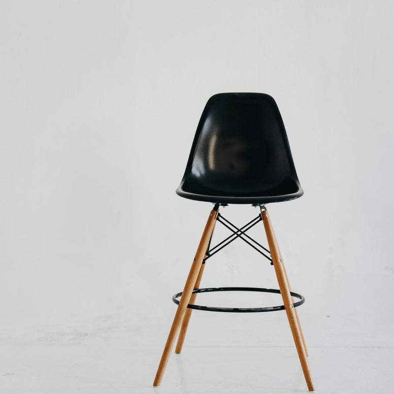 Black shell bar stool on wooden legs with a black metal footrest